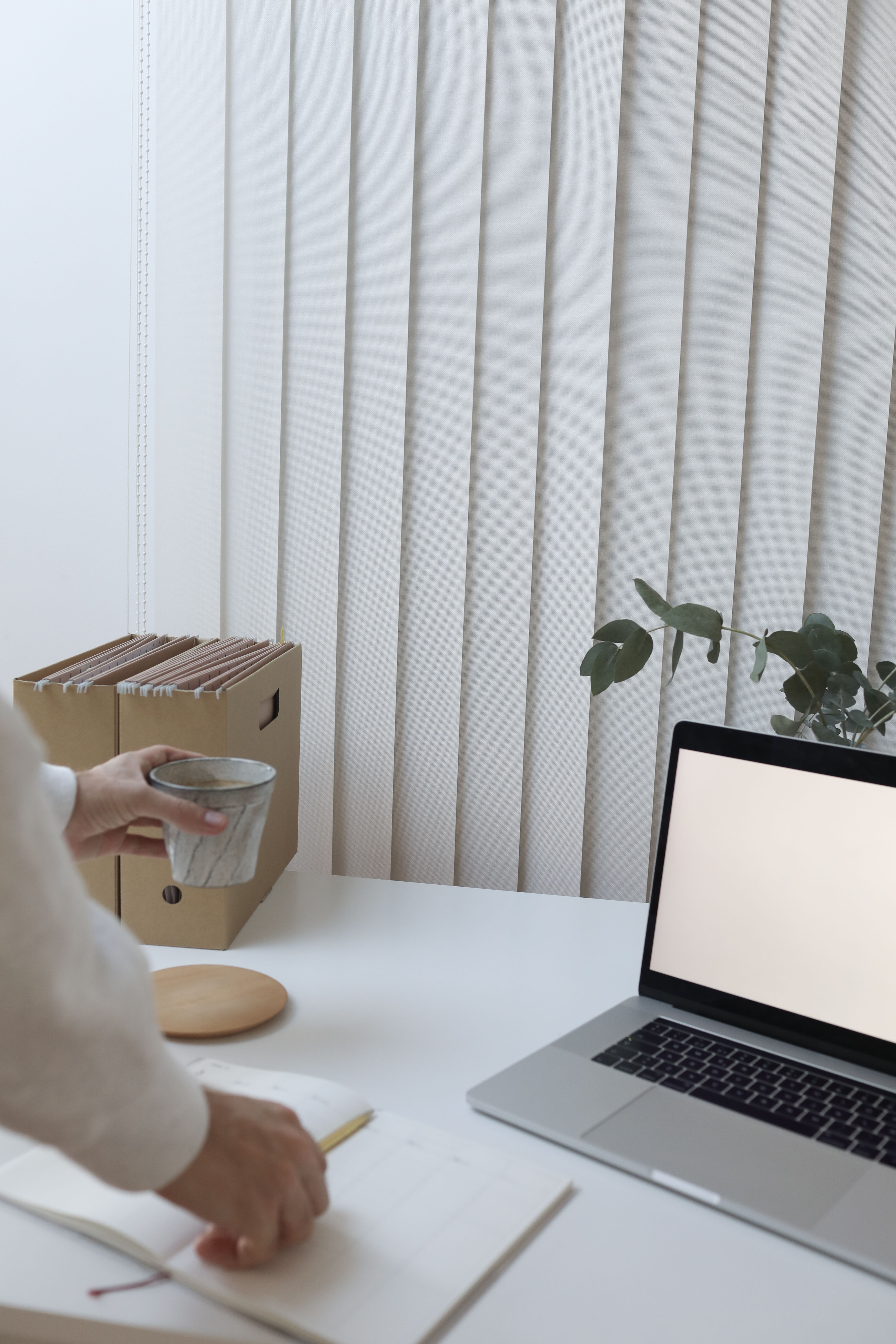 Writing notes at a desk with a coffee and laptop